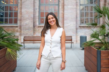 İş kadını modern bir şehir bağlamında rahat bir şekilde gülümsüyor.