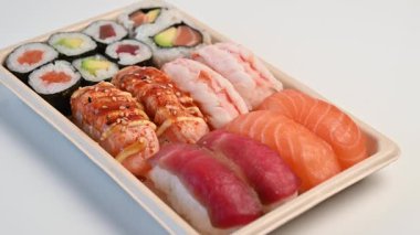 Lezzetli geleneksel Japon yemek tabağı servis ya da paket servis için beyaz bir zemin üzerinde dönüyor.