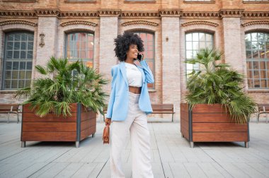 Businesswoman talking on the phone while walking in a modern urban context