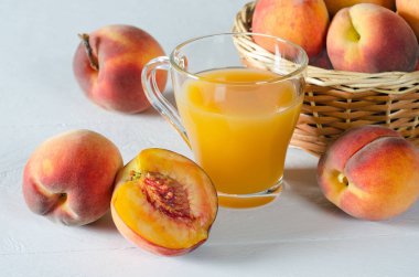 Şeftali suyu bir cam kabı ve beyaz bir tablo olgun şeftali.