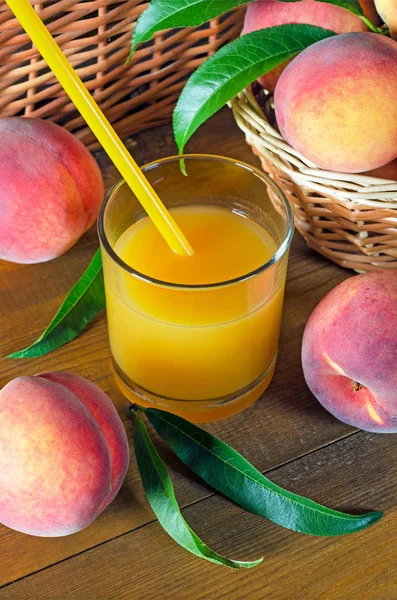 Peach juice in a glass beaker and juicy ripe peaches on a wooden table. Rustic style.