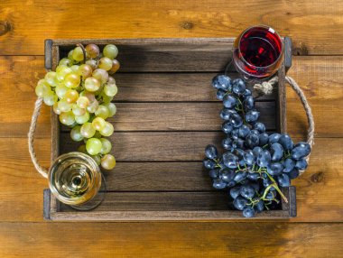 Kırmızı ve beyaz şarap ve üzüm ahşap arka plan üzerinde bir kutu içinde bardak. Üstten görünüm, boşluk.