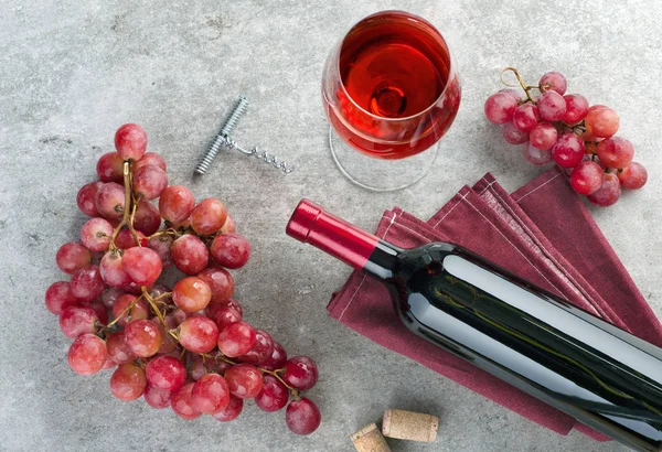 Bottiglia, bicchiere di vino, uva e cavatappi su tavola grigia . — Foto Stock