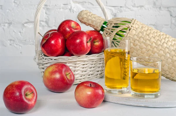 Червоні яблука і сік в окулярах на білому столі . — стокове фото