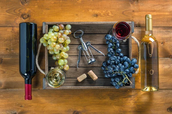 Dvě lahve vína a hroznů v poli na dřevěné pozadí. — Stock fotografie