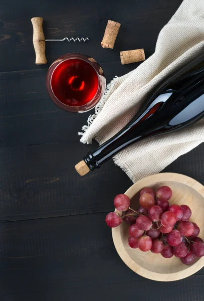 Bottiglia di vino, bicchiere di vino, uva e cavatappi su tavola scura . — Foto Stock