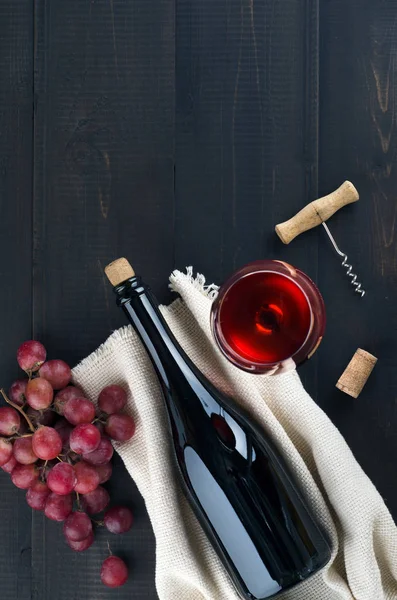 Bottiglia di vino, bicchiere di vino, uva e cavatappi su fondo scuro — Foto Stock