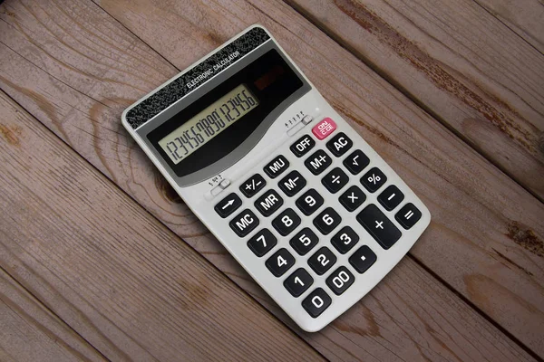 LED display electronic calculator on wooden background.