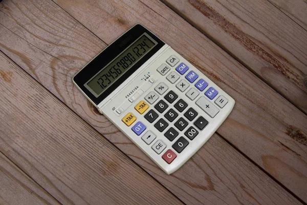 LED display electronic calculator on wooden background.