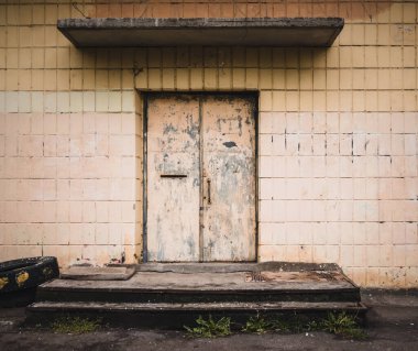 Eski ahşap kapı. Kırmızı boya ile boyanmış. Arka planda beyaz fayanslar var.