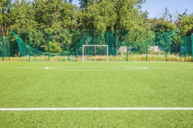 Okulun yakınında yapay yeşil çimenler olan bir futbol sahası. Amatör futbol sahası. Güneşli yaz günü
