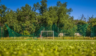 Okulun yakınında yapay yeşil çimenler olan bir futbol sahası. Amatör futbol sahası. Güneşli yaz günü