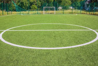 Okulun yakınında yapay yeşil çimenler olan bir futbol sahası. Amatör futbol sahası. Güneşli yaz günü