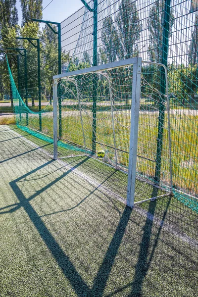 Goal on a football field with artificial green grass near the school. Amateur football field. Sunny summer day