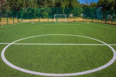 Okulun yakınında yapay yeşil çimenler olan bir futbol sahası. Amatör futbol sahası. Güneşli yaz günü