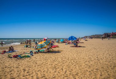 Ukrayna, Kyiv - 4 Ağustos 2020. Sıcak yaz günlerinde Ukrayna 'nın Hrybivka kentindeki plaj manzarası, Odessa yakınlarındaki turistler, güneşlikler ve şemsiyeler. Karadeniz