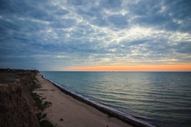 Bulutlu bir sabahta denizde şafak öncesi gökyüzü. Gemiler ufukta gün doğumunun arka planında görülebilir. Kumlu sahil şeridini bırakıyorum. Karadeniz. Sanzhiika. Ukrayna