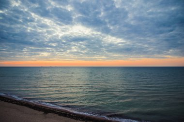 Bulutlu bir sabahta denizde şafak öncesi gökyüzü. Gemiler ufukta gün doğumunun arka planında görülebilir. Kumlu sahil şeridini bırakıyorum. Karadeniz. Sanzhiika. Ukrayna