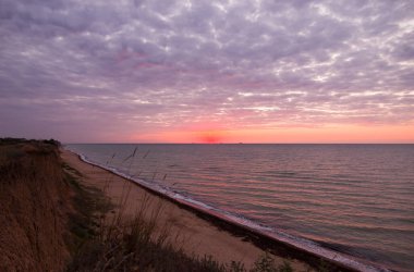 Bulutlu bir sabahta denizde güzel bir gün doğumu. Gemiler ufukta gün doğumunun arka planında görülebilir. Kumlu sahil şeridini bırakıyorum. Karadeniz. Sanzhiika. Ukrayna