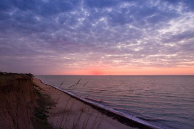 Bulutlu bir sabahta denizde güzel bir gün doğumu. Gemiler ufukta gün doğumunun arka planında görülebilir. Kumlu sahil şeridini bırakıyorum. Karadeniz. Sanzhiika. Ukrayna