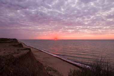 Bulutlu bir sabahta denizde güzel bir gün doğumu. Gemiler ufukta gün doğumunun arka planında görülebilir. Kumlu sahil şeridini bırakıyorum. Karadeniz. Sanzhiika. Ukrayna