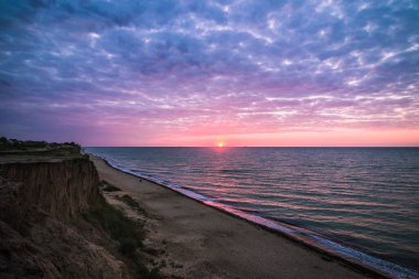 Bulutlu bir sabahta denizde güzel bir gün doğumu. Gemiler ufukta gün doğumunun arka planında görülebilir. Kumlu sahil şeridini bırakıyorum. Karadeniz. Sanzhiika. Ukrayna