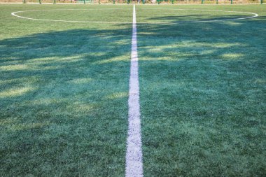 Okulun yakınında yapay yeşil çimenler olan bir futbol sahası. Amatör futbol sahası. Güneşli yaz günü