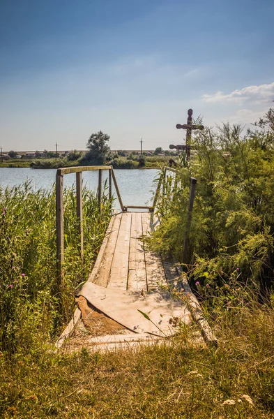 Wooden walkway on the pond. A wooden deck on a pond. A lake and an old wooden bridge