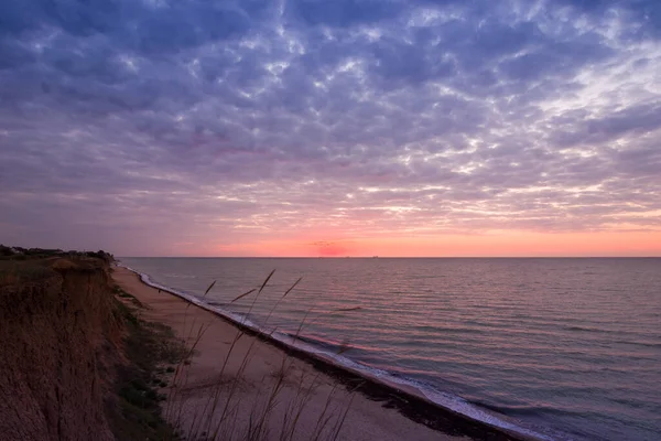 Bulutlu bir sabahta denizde güzel bir gün doğumu. Gemiler ufukta gün doğumunun arka planında görülebilir. Kumlu sahil şeridini bırakıyorum. Karadeniz. Sanzhiika. Ukrayna