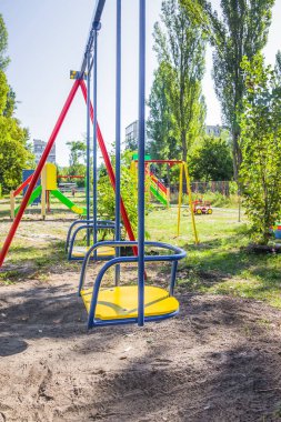 Yeşil ağaçlarla çevrili parktaki renkli çocuklar oyun parkı aktiviteleri