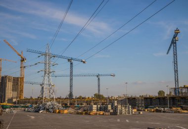 Mavi gökyüzünün arka planında sirrus bulutları olan birçok vinç bulunan bir alışveriş merkezi inşaatı. Kyiv. Obolon