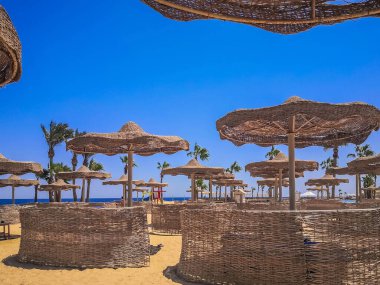 Güzel deniz kıyıları. Deniz kıyısında bir sahil. Wicker plaj şemsiyeleri ve rüzgar çitleri. Plaj tatilinin kavramsal görüntüsü.