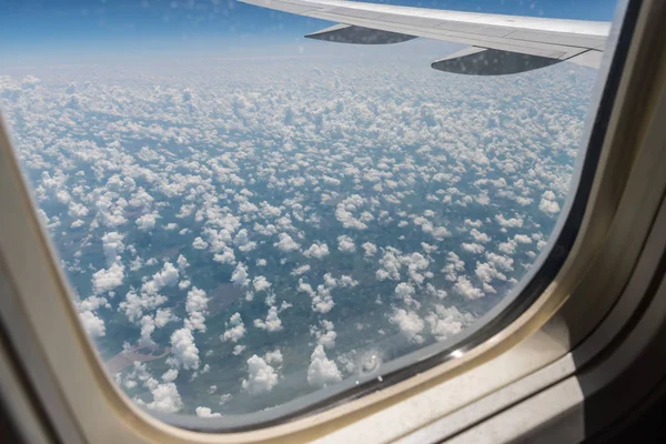 从飞机机翼的舱门、下面的地面和夏季飞行的云层中观看 — 图库照片