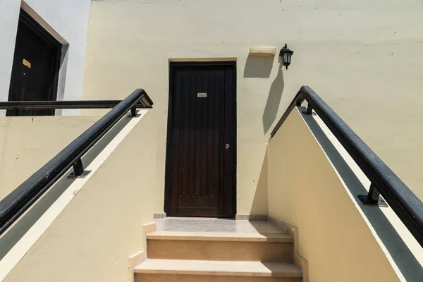 Karanlık kapılı parlak bir bina. Otel odasına giden merdivenler. Otel odasındaki kapılar.