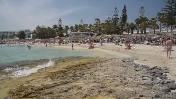 AGIA NAPA, CYPRUS - 26 Mayıs 2019: Nissi Plajı Panoraması 'nın el yapımı çekimi. Kıbrıs Rum Kesimi Ayia Napa şehri Nissi plajı. İnsanlar deniz kıyısında dinleniyor.. — Stok video