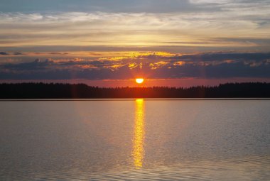 Imatra, ağır bulutları içinde düşük yükselen güneş bir göl üzerinde erken dawn güzel