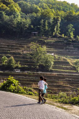 İki köyün gençleri rice terraces adlı Yuanyang yanında pis bir yol kenarındaki yürüyüş