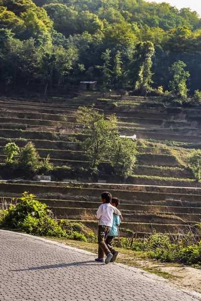 İki köyün gençleri rice terraces adlı Yuanyang yanında pis bir yol kenarındaki yürüyüş