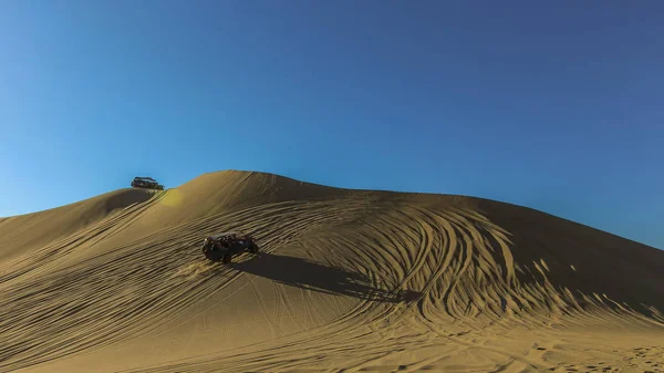 Huacachina, Peru 'da mavi gökyüzüne karşı kum tepeleri ve arabaları