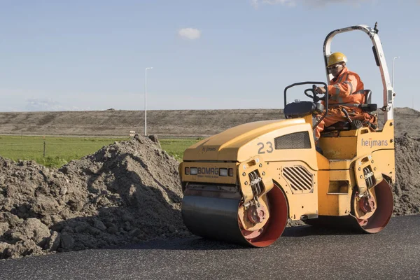 Grootebroek, Hollanda 3 Mayıs 2018: erkekler çalışan yeni bir yol yapımı için kullanılan bir asfalt silindiri üzerinde