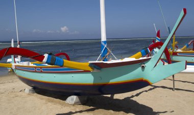 Koyu mavi renkli balıkçı teknesi ile yeşil beyaz Sanur beach Bali Endonezya yatıyor. Endonezya dili arka planda da Denizi ile deniz.