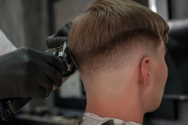 Barbershop. Close-up of man haircut, master does the hair styling in barber shop