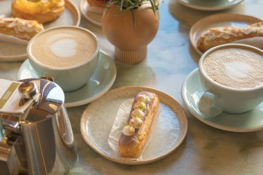 Cafe masa bardak kahve, eklerleri ve kek ile