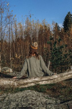 Sırt çantalı hippi genç kız sisli dağın zirvesinde günbatımının tadını çıkarıyor. Arka planda turist modeli var. Gezgin gün ışığına bakıyor