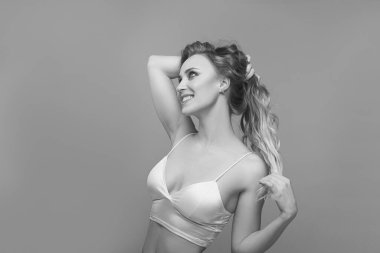 Parlak göz makyajlı ve kıvırcık sarı saçlı genç bir kadının siyah beyaz bir portresi.