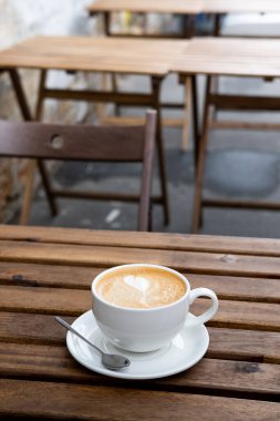 Cappuccino ya da Latte sanat kahvesi kahve dükkanının açık terasındaki ahşap masadaki sütten yapılır.