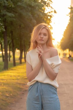 Gün batımında düz sarı saçlı genç bir kadının açık hava moda portresi.