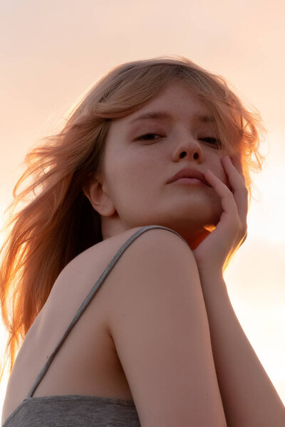 Outdoor fashion portrait of a  young woman with with straight blond hair at sunset