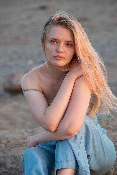 Outdoor fashion portrait of a  young woman with with straight blond hair at sunset