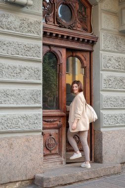 Bir binanın merdivenlerinde genç bir kadının açık hava moda portresi. Şehirde şık, esmer bir kadının fotoğrafı var. Moda sonbahar bahar bahar fotoğrafı